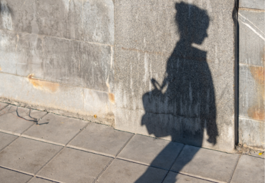 Photo: The shadow of a young person wearing a backpack is outlined against a wall
