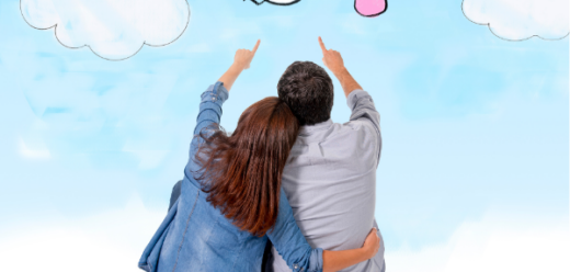 Photo of a seated couple pointing at the image of a stork carrying a pink bundle.