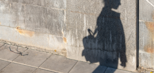 Photo: The shadow of a young person wearing a backpack is outlined against a wall